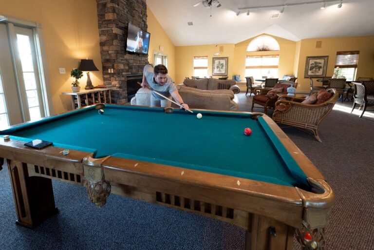 Man in shooting pool in clubhouse.