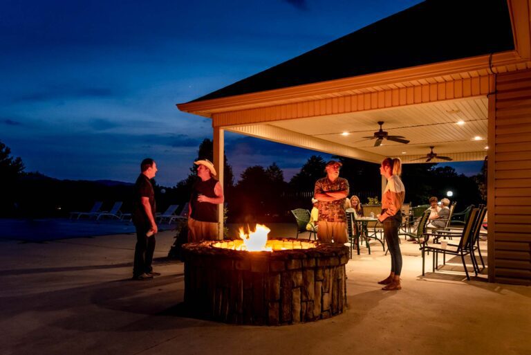 People standing around a fire pit after sunset.