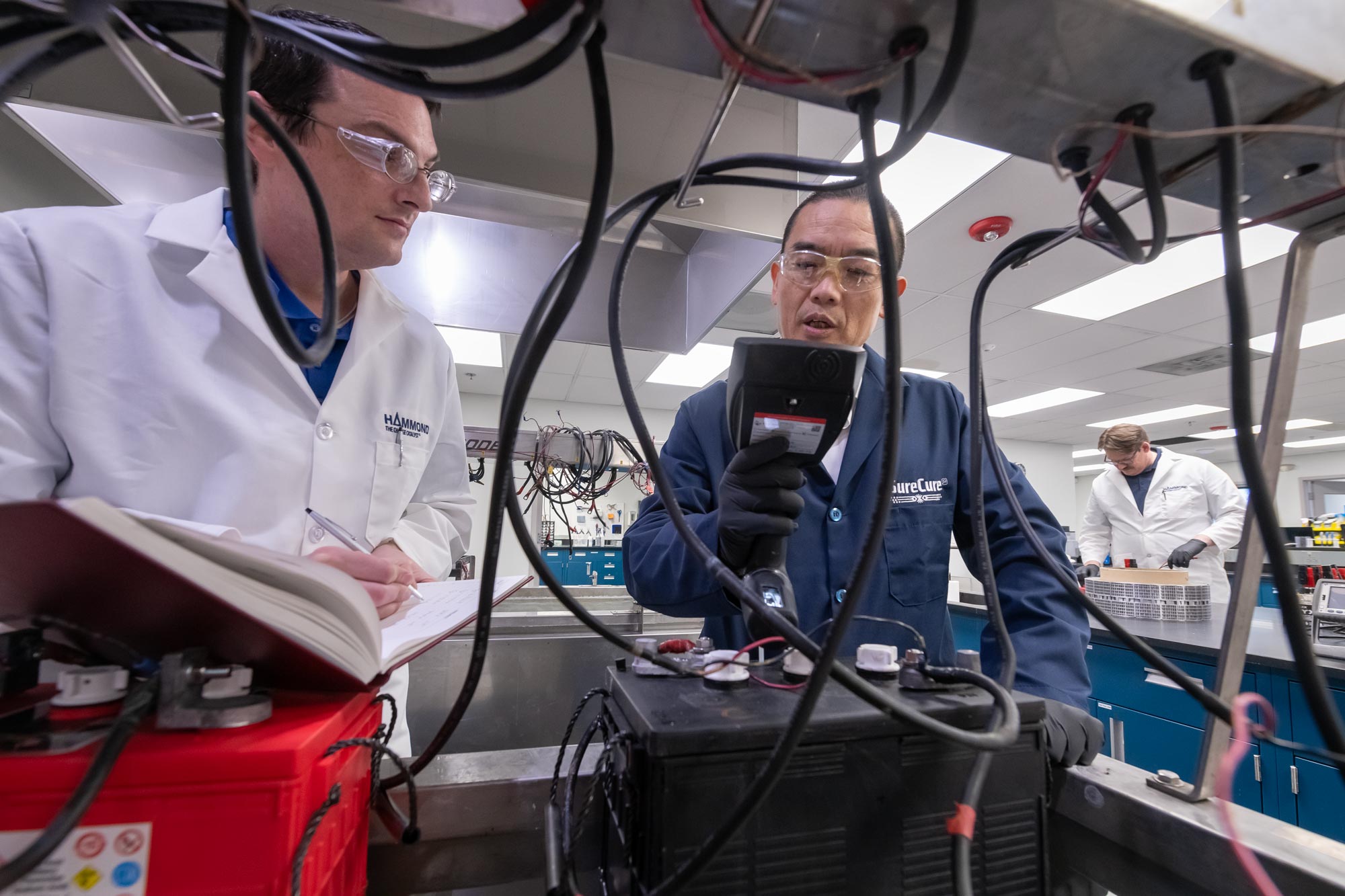 Men in lab coats working with batteries and testing equipment.