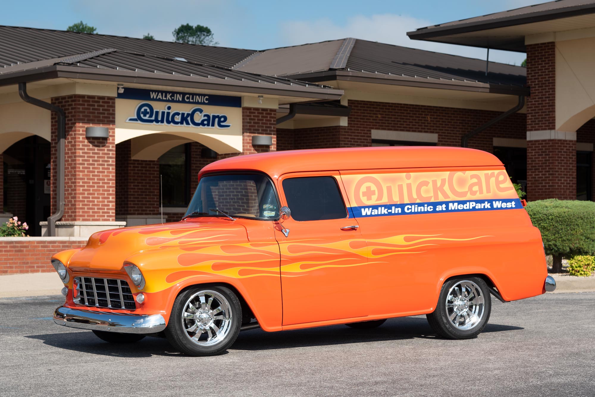 Antique van wrapped in QuickCare branding graphics in front of QuickCare clinic