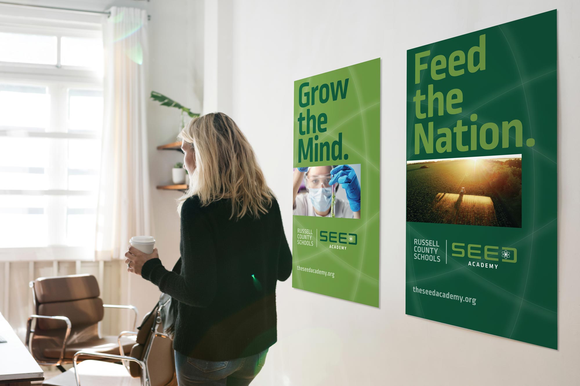 Teacher in a classroom with two SEED ACADEMY posters on the wall. "Grow the Mind" and "Feed the Nation"