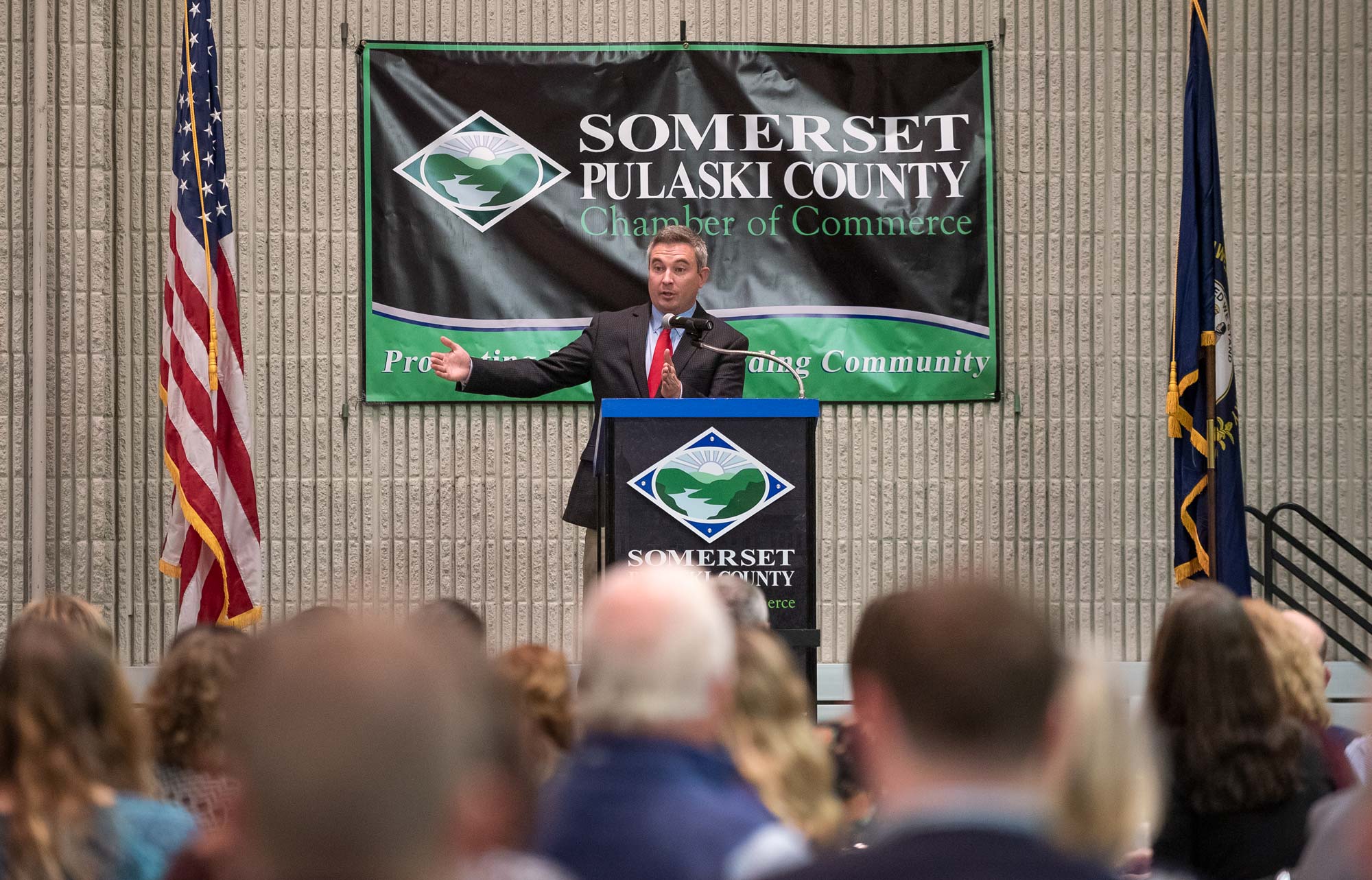 Man speaking from behind a podium to a large crowd of people