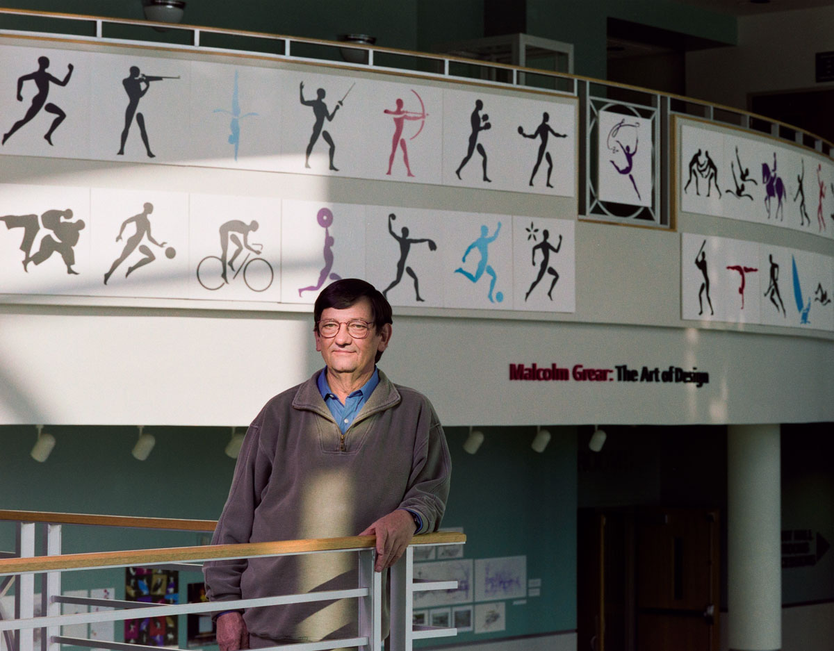 Man with Olympic pictogram symbols behind on the wall