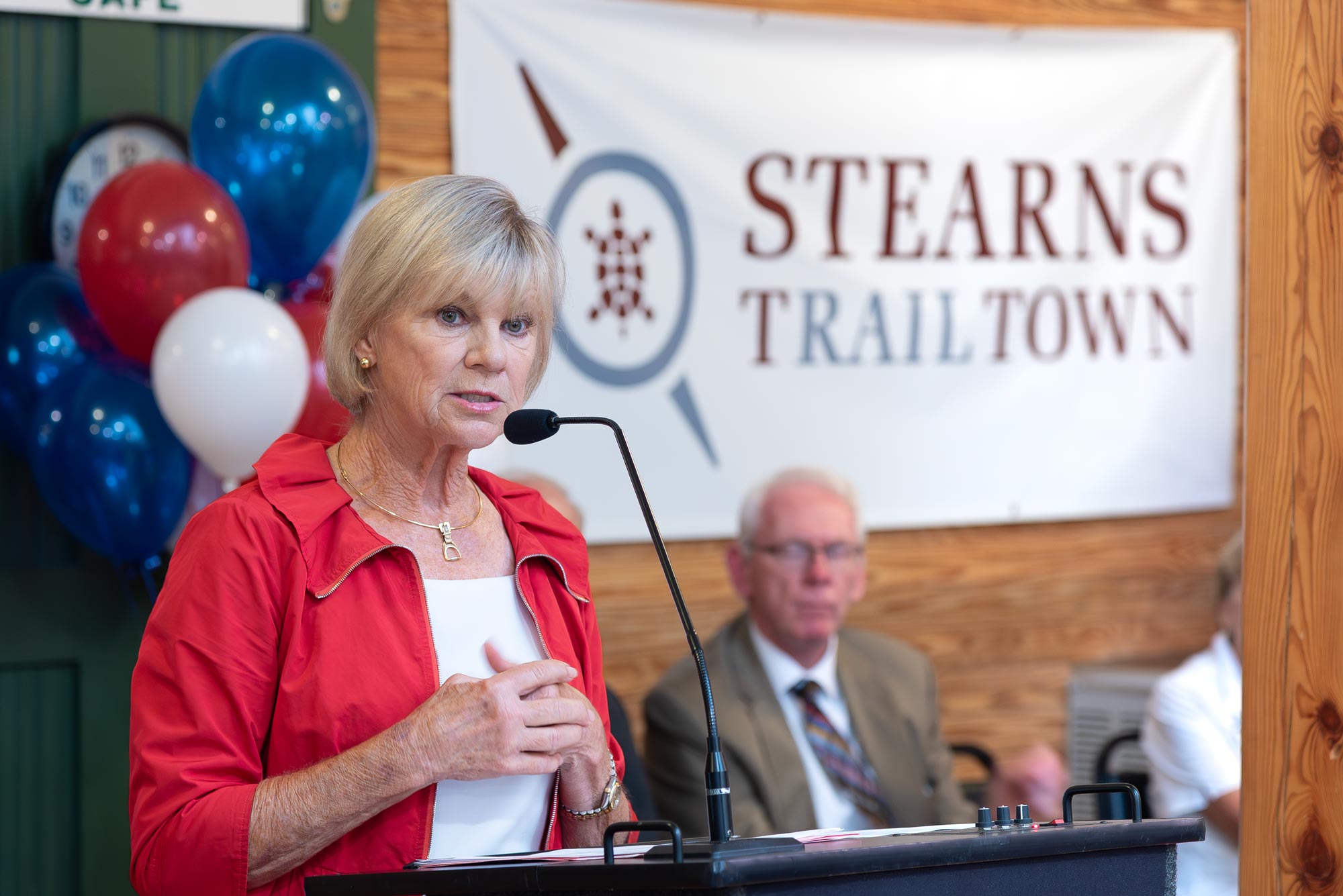 Woman at podium with Stearns Trail Town banner in background