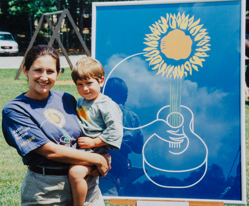 Erin and Issac Stephens with Master Musicians Festival Artwork of a guitar and flower illustration