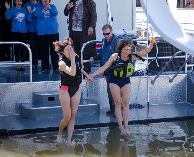 Two women jumping from a platform into cold water