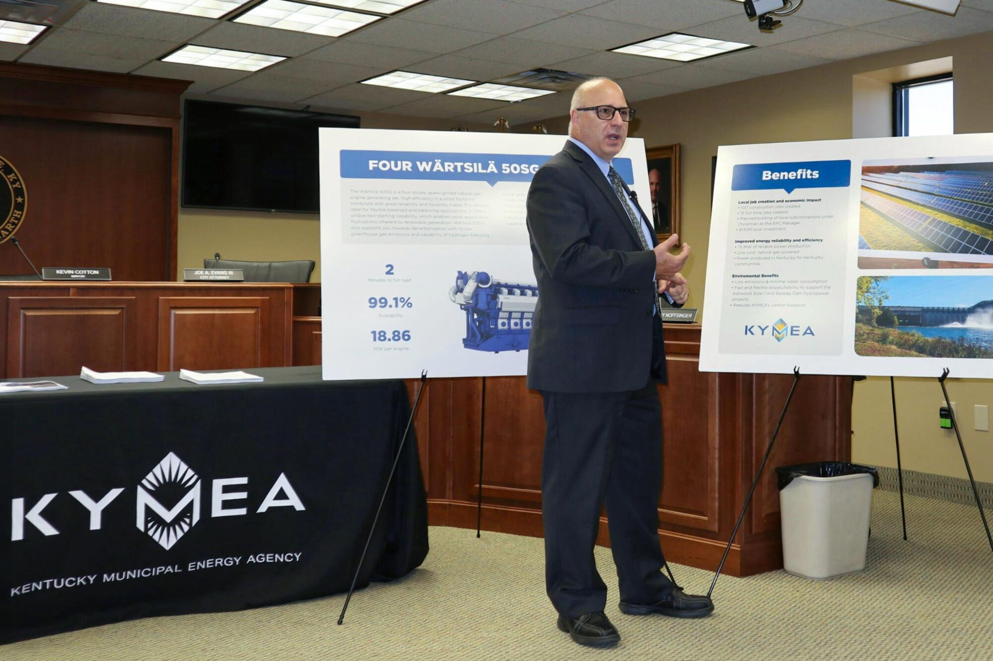 Man with info graphic displays and branded KTMEA table