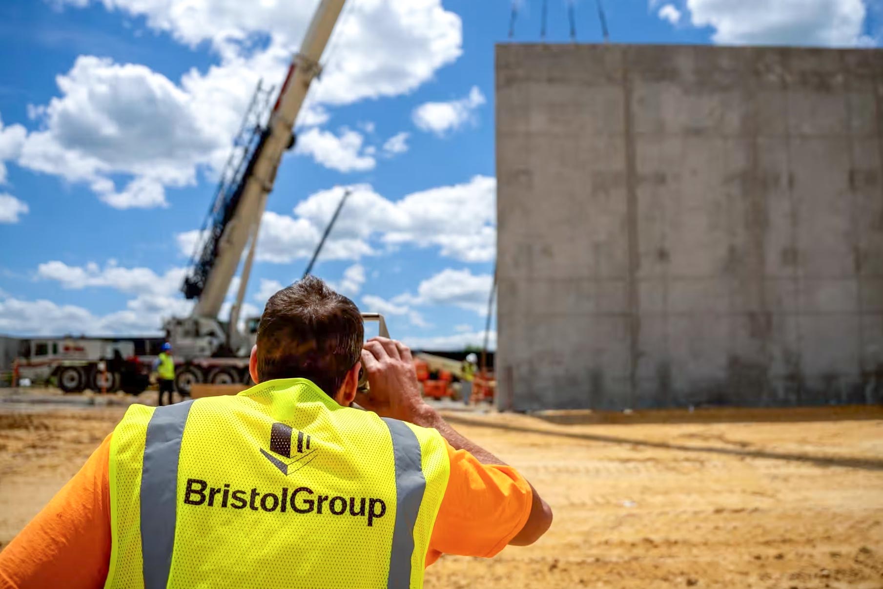 Surveyor wearing Bristol Group safety vest at construction site