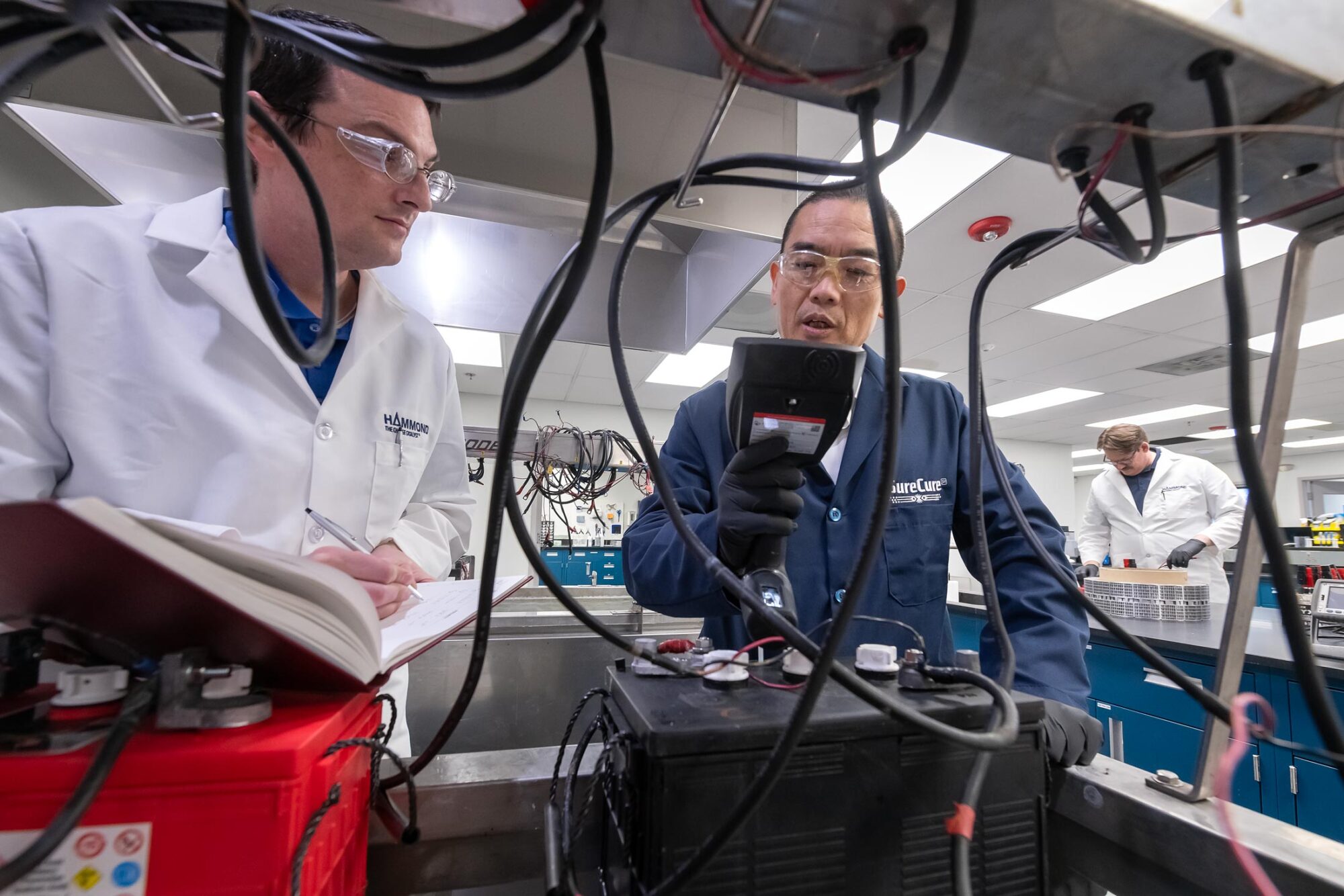 Men in lab coats working with batteries and testing equipment.