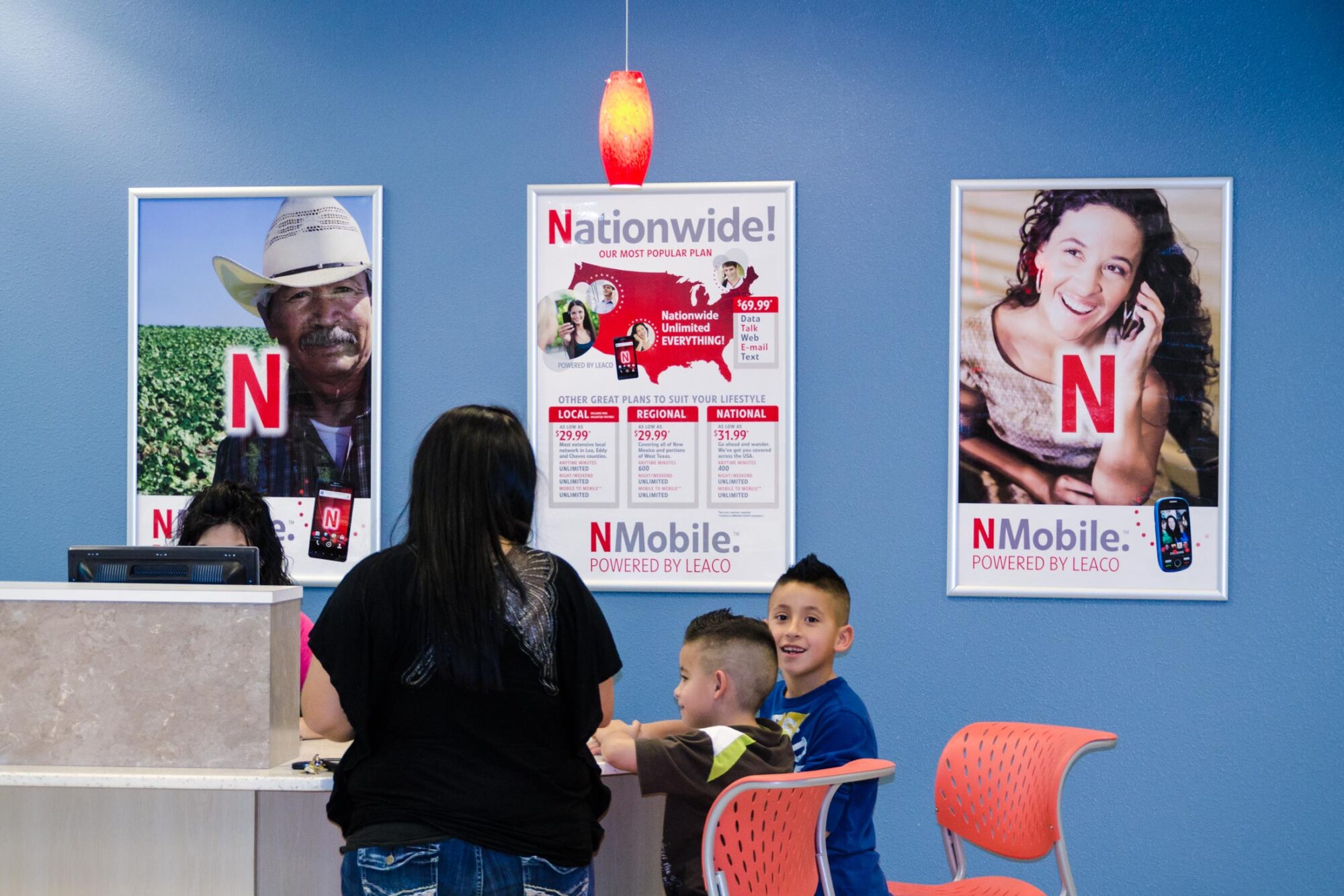 Customers at a service counter with NMobile posters on the wall.