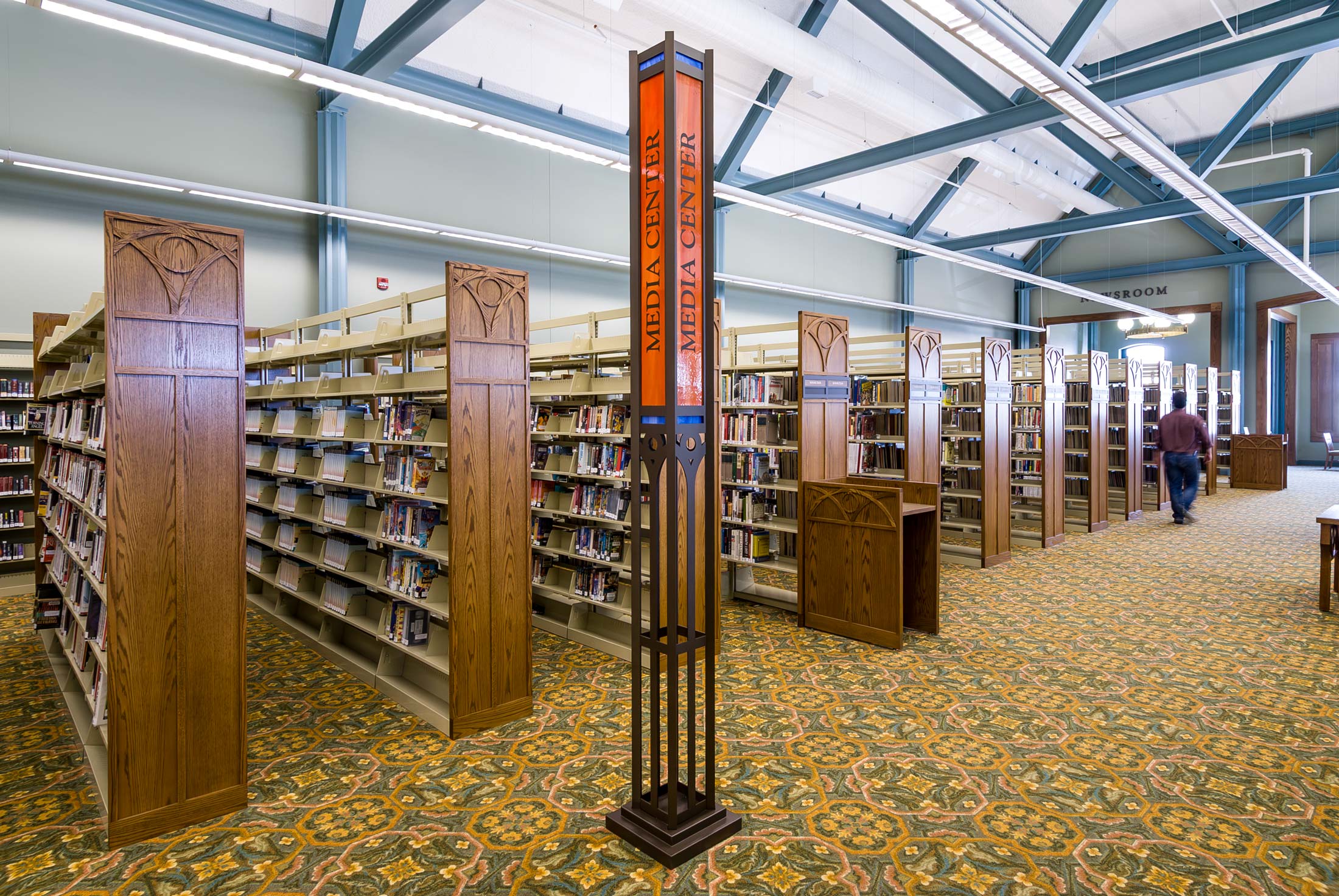 Library interior with tall, thin metal and stained glass section sign.