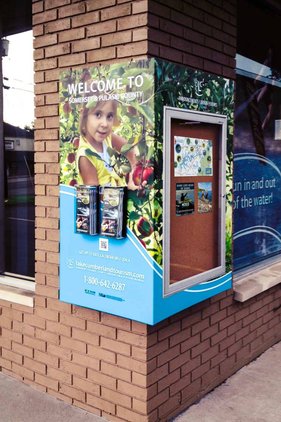 building corner mounted sign with builtin board, sign graphics, and brochure rack
