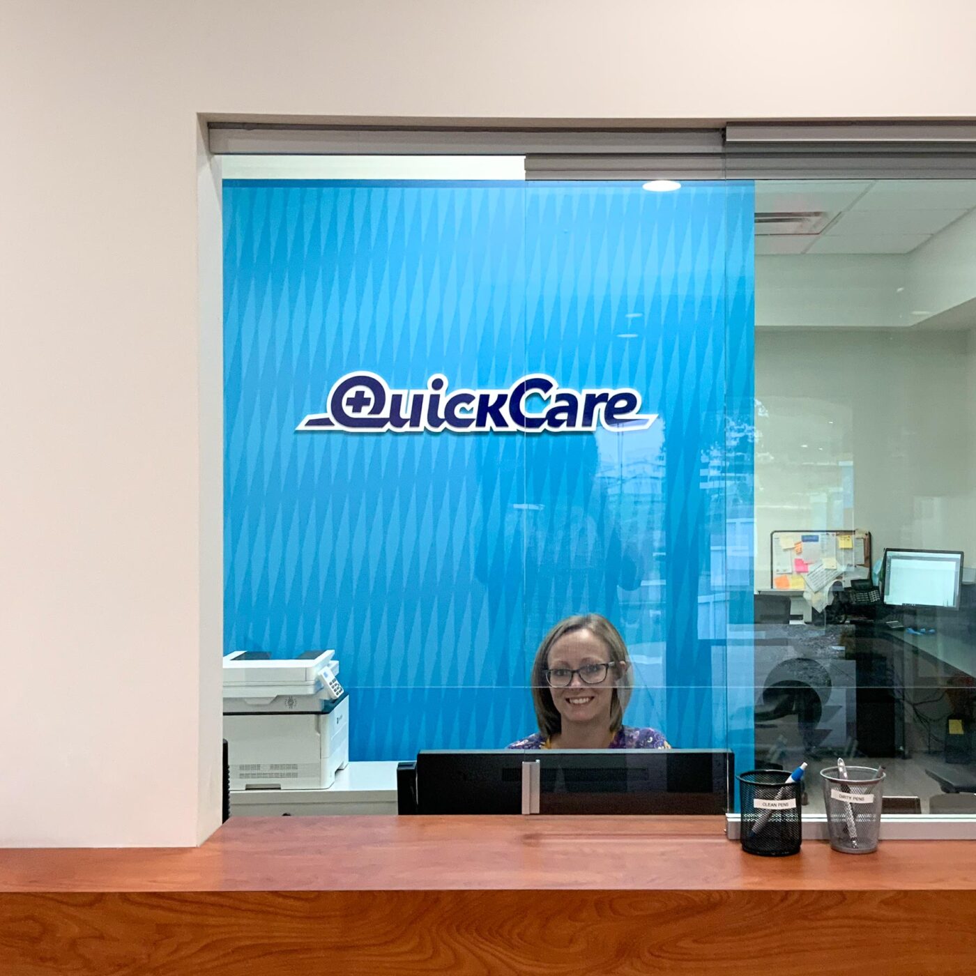 QuickCare dimensional logo on a graphic pattern behind the reception desk.