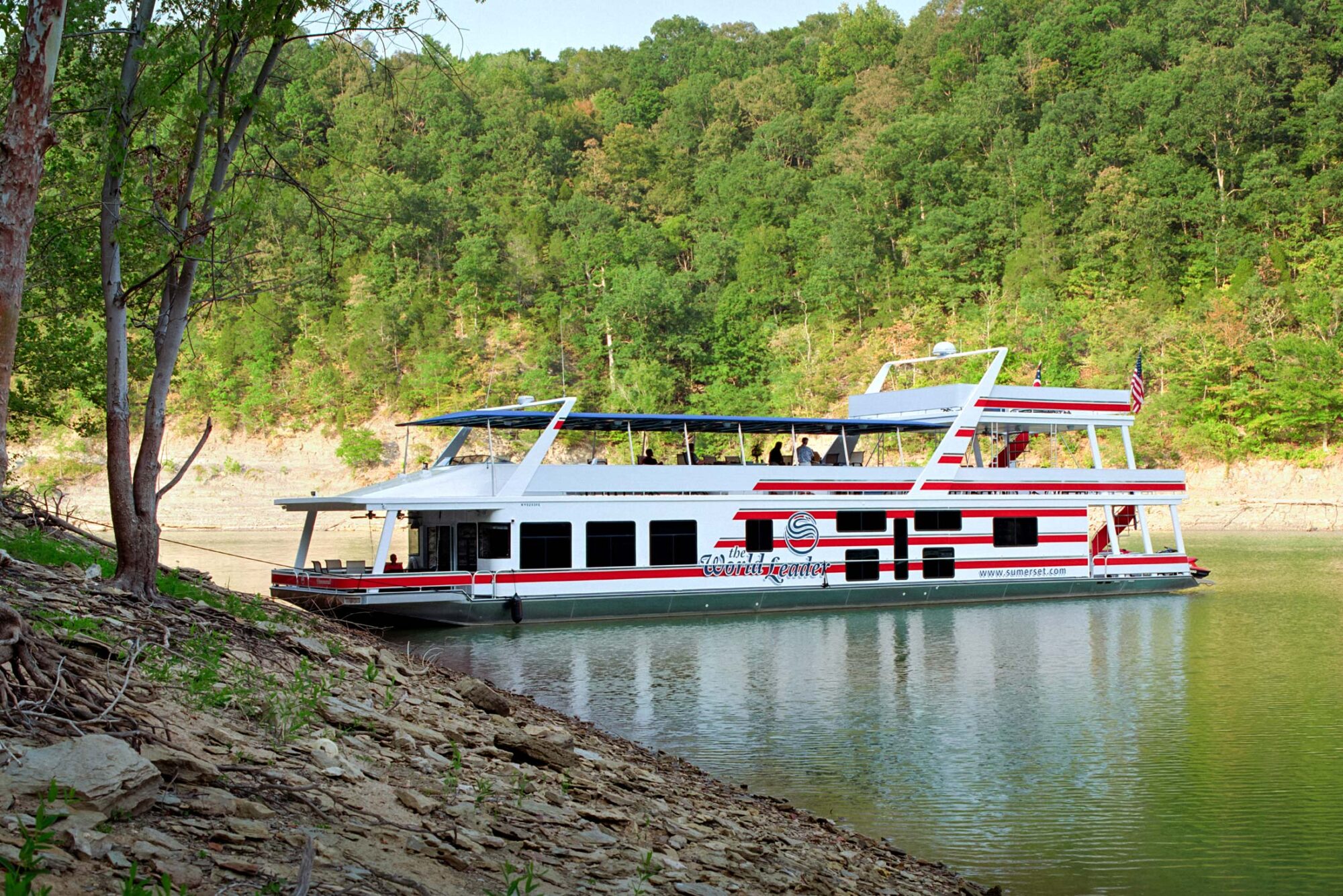 Large houseboat on lake with Sumerset logo slogan "The World Leader" on the side